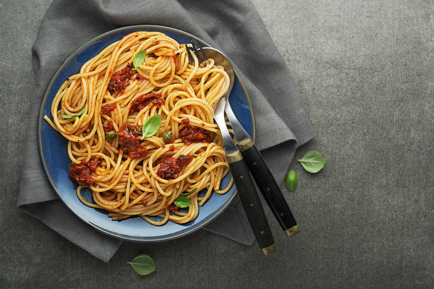Delicious meal with spaghetti and tomato sauce with basil served on gray background - Foto, immagini