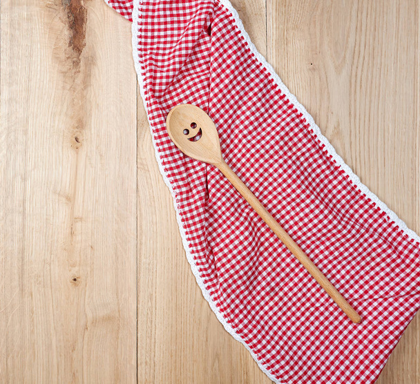 red towel and spoon on brown wooden background, top view - 写真・画像