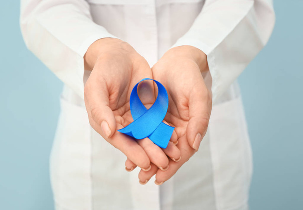 Γυναίκα ουρολόγος με μπλε κορδέλα στο φόντο χρώμα, closeup. Έννοια του καρκίνου του προστάτη - Φωτογραφία, εικόνα