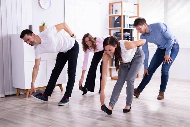 Group Of Happy Young Businesspeople Doing Stretching Exercise In Office - Valokuva, kuva