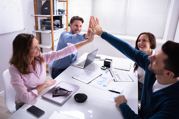 Group Of Happy Businesspeople Giving High Five Over Desk At Workplace - Valokuva, kuva
