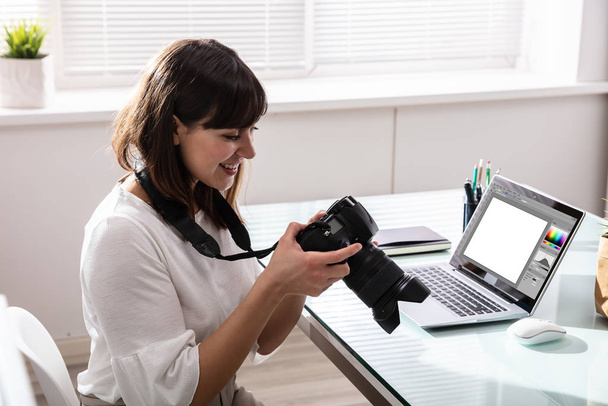 Close-up Of An Editor Looking At Photograph In DSLR Camera At Workplace - Foto, afbeelding