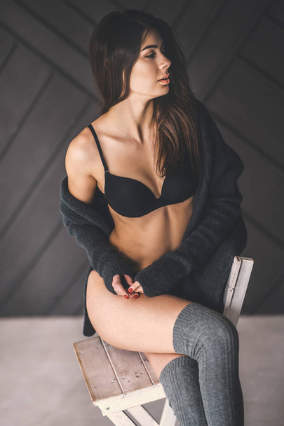 Young brunette in black underwear, knitted knee pads and cardiga - Foto, Imagen