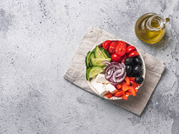 灰色のセメントの背景にギリシャのサラダボウル、コピースペース。ボウルギリシャサラダの上のビュー。トレンディな食べ物。現代の健康食品のアイデア、受信と概念. - 写真・画像