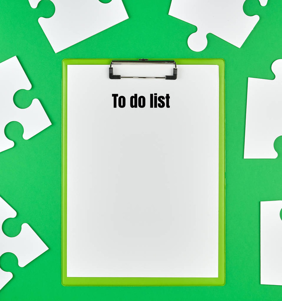 paper clip and white large paper puzzles on a green background, top view - Foto, immagini