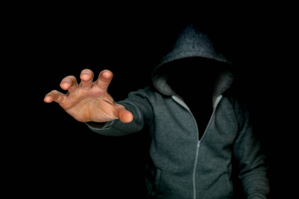 An unknown man in a hood reaches with his hand with his terrible hand - Foto, Imagem