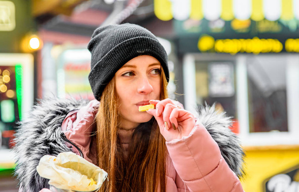 Young Woman Eating A French Fries Street food outdoor winter - Foto, Imagen