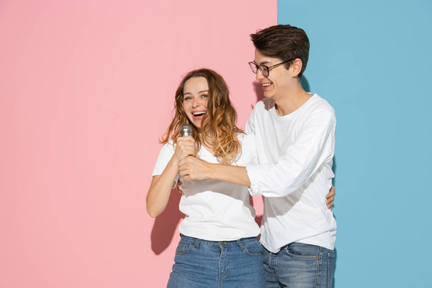 Young emotional man and woman on pink and blue background - Photo, image