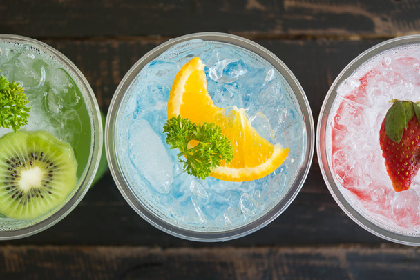 Green Blue Red Italian Soda Cold Beverage and Kiwi Lemon Strawberry Fruit and Parsley. Green Blue Red Italian Soda Cold Beverage on wood table for food and drink category - Foto, imagen