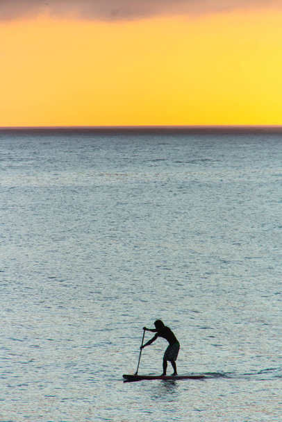 sylwetka człowieka z jego stand up wiosło z pięknym tle zachód słońca na plaży Ipanema. - Zdjęcie, obraz