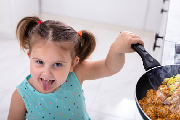 Mosolygó kis csinos lány játszik forró főzés Pan a konyhában - Fotó, kép