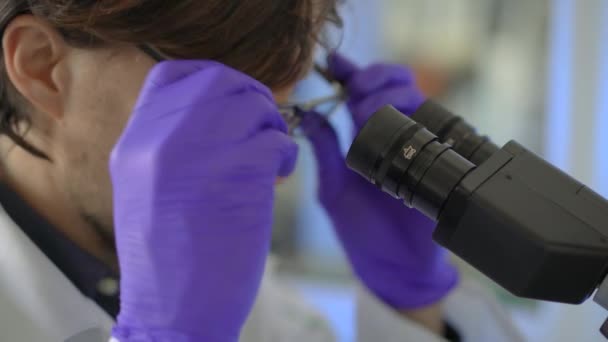 Scientist in a laboratory uses a microscope. Closeup shot - Πλάνα, βίντεο