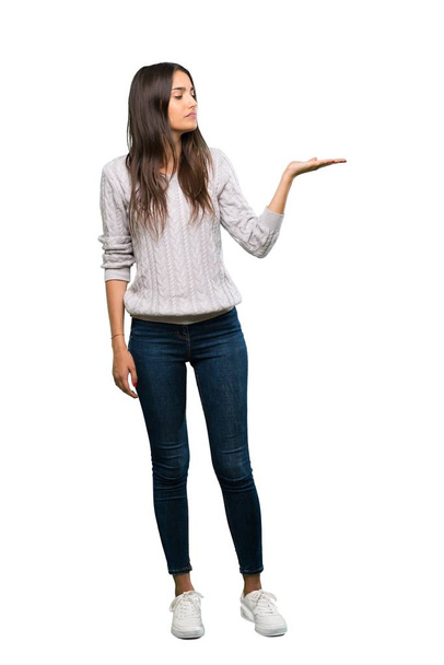 A full-length shot of a Young hispanic brunette woman holding copyspace with doubts over isolated white background - Fotografie, Obrázek