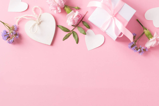 Presente, coração branco de madeira e flores no fundo rosa
 - Foto, Imagem