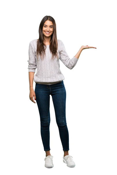 A full-length shot of a Young hispanic brunette woman holding copyspace imaginary on the palm to insert an ad over isolated white background - Foto, Bild