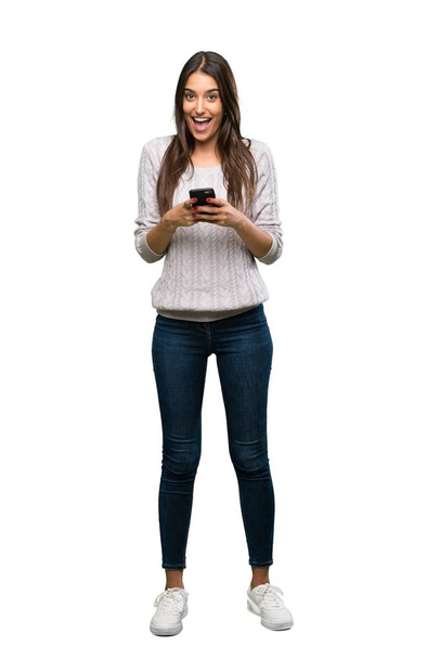 A full-length shot of a Young hispanic brunette woman surprised and sending a message over isolated white background - Foto, Bild