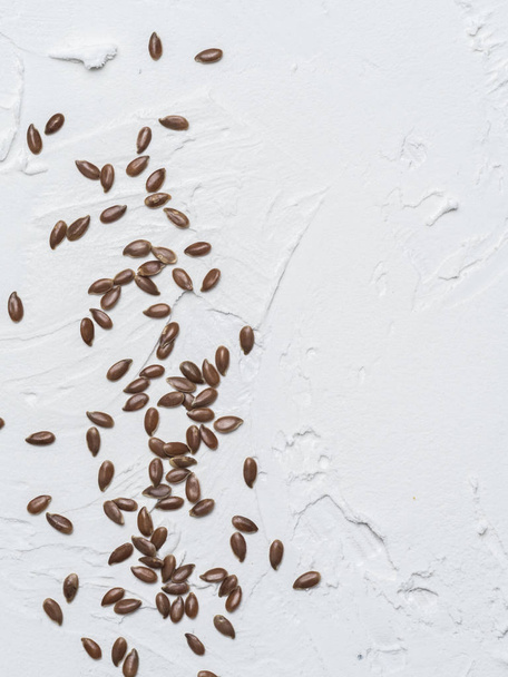 Flax seeds with copy space. Brown flax seed on white concrete textured background. Top view or flat lay. Copy space. Vertical - Foto, Imagem