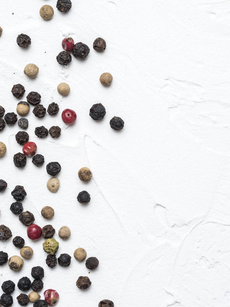 Assorted peppercorns. Medley trio colorful peppercorn on white textured concrete background with copy space. Top view or flat lay. Vertical - Foto, immagini