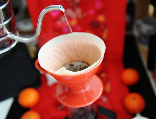 Ο κινέζικος καφές είναι ζωντανός. Χειροκίνητη ζυθοποιία, κόκκινο σταγονόμετρο. Παραδοσιακό μοτίβο υφάσματος. Μανταρίνια σε φόντο - Φωτογραφία, εικόνα