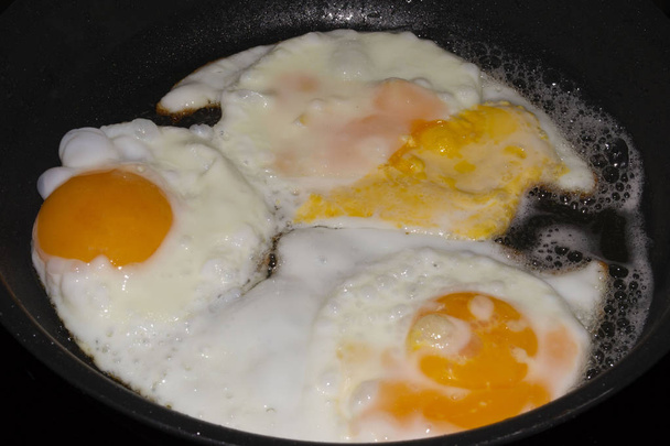tři smažená vejce v pánvi s olivovým olejem. - Fotografie, Obrázek