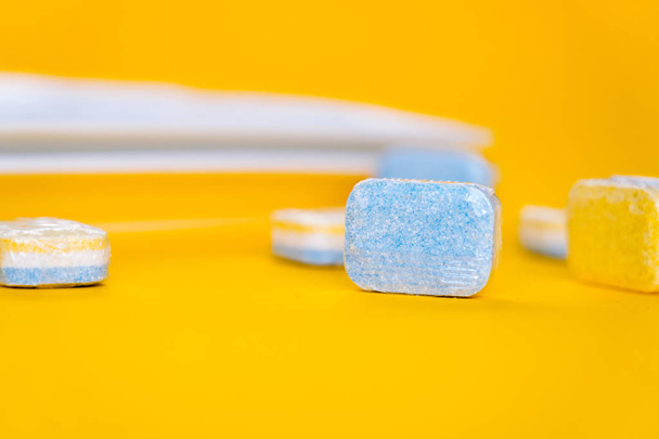 Чистка посудомоечных таблеток с белой тарелкой на желтой спине
 - Фото, изображение