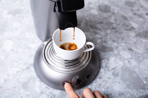 Close-up Of Person's Hand Pressing The Button On A Coffee Maker Taking Coffee - Foto, afbeelding