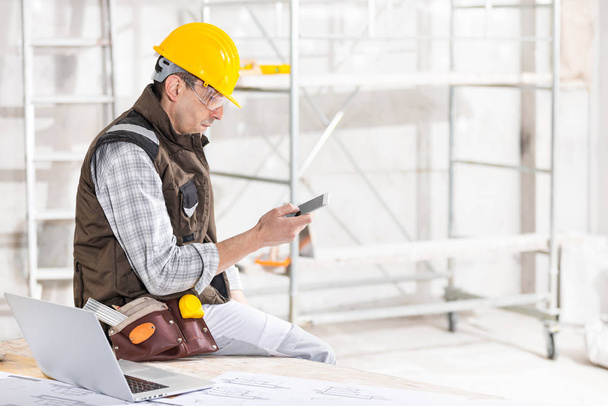 Builder or contractor using a mobile phone on site - 写真・画像