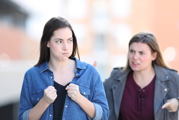 Front view portrait of two angry friends arguing in the street - Foto, Imagen