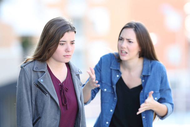 Angry woman scolding her guilty friend in the street - Foto, imagen
