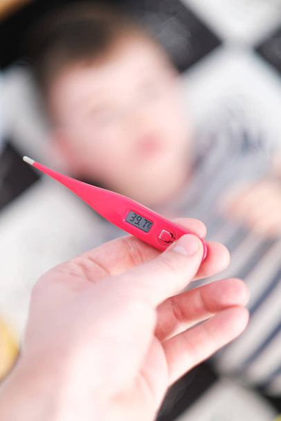 Little baby boy has got a flu. Hand holding a thermometer. - 写真・画像