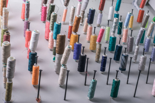 разноцветные нити для шитья, в больших количествах, в швейной мастерской, под необычным углом обзора. Абстрактный фон из ниток
 - Фото, изображение
