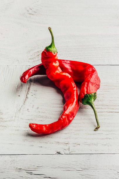 Ripe and red chili peppers over light wooden background. - Photo, Image
