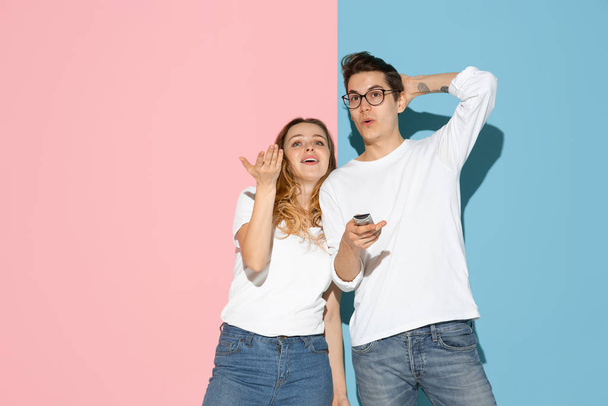 Young emotional man and woman on pink and blue background - Foto, imagen