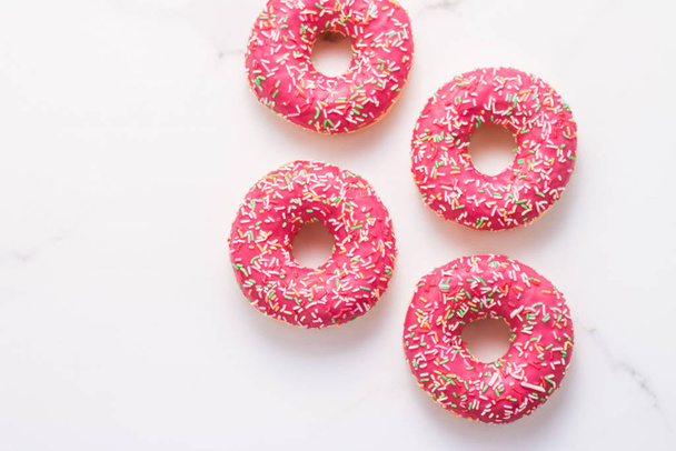 Frosted sprinkled donuts, sweet pastry dessert on marble table b - Photo, Image