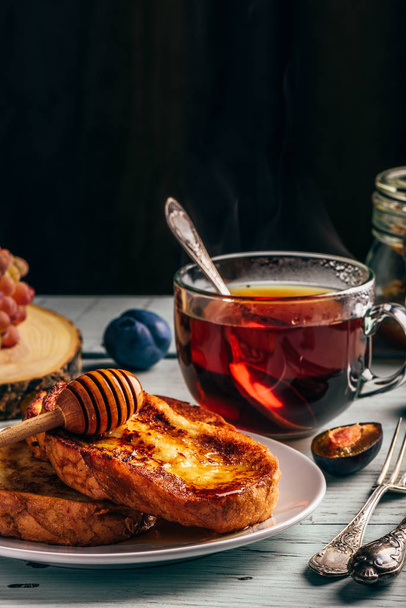 Healthy breakfast concept. French toasts with honey, fruits and tea over white wooden background - Fotó, kép