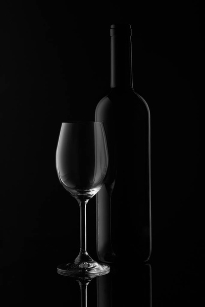 Silhouette of wine bottle and empty wineglass on a black background with reflection.  Contour with gradient and highlights - Fotó, kép