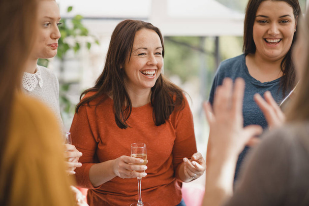 Small group of female friends celebrating at a house party. They are enjoying a glass of champagne, laughing and smiling. - Foto, Bild
