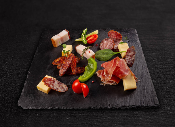 Breakfast with delicious salami, pieces of sliced prosciutto served on black slate - Φωτογραφία, εικόνα