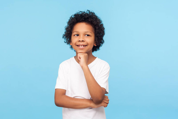 Portrait of thoughtful happy little boy in T-shirt standing with - Photo, Image