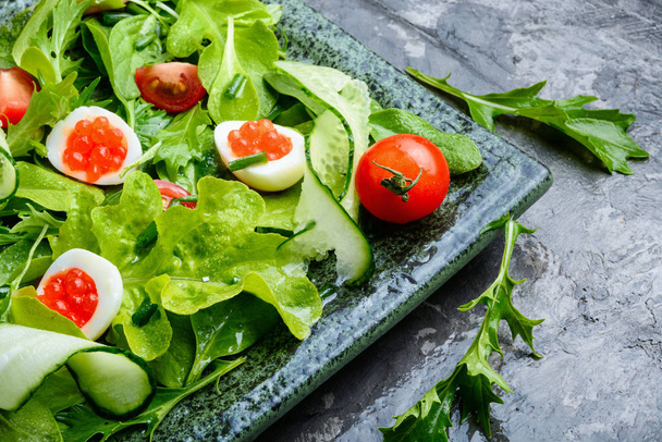 Spring vegetable salad with greens, cucumber, egg and red caviar - Фото, зображення