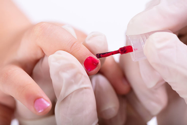 Close-up Of Beautician's Hand Applying Nail Polish To Girl's Nails At Beauty Salon - Фото, зображення