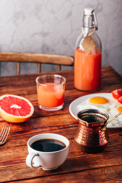 Breakfast with turkish coffee, fried eggs, juice and fruits over wooden table - Foto, afbeelding