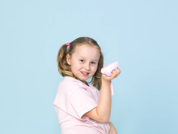 beautiful 8 year old girl is playing with pink slime in front of blue background - Foto, immagini