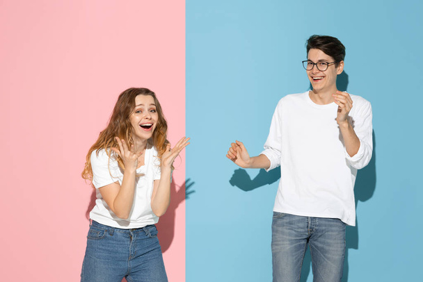 Young emotional man and woman on pink and blue background - Фото, изображение