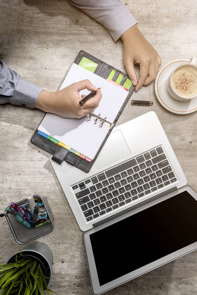 Top widok biznesmen piśmie w Notatniku z laptopem, kawą, doniczkowe i akcesoria biznesowe na biurku - Zdjęcie, obraz