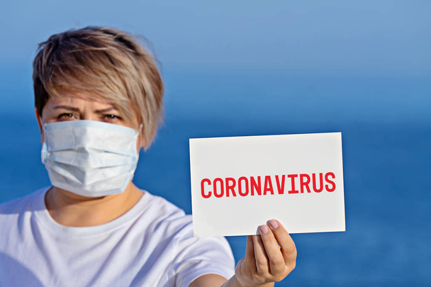Cerrahi maskeli kadın, Coronavirus 2019 metni ile boş duruyor. - Fotoğraf, Görsel