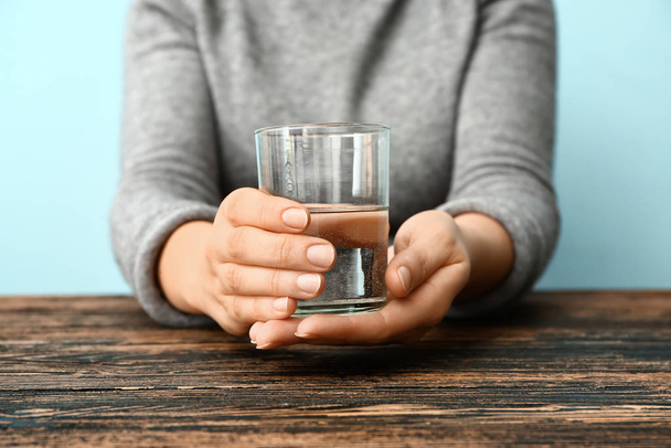 Vrouw met Parkinson syndroom met glas water aan tafel, close-up - Foto, afbeelding