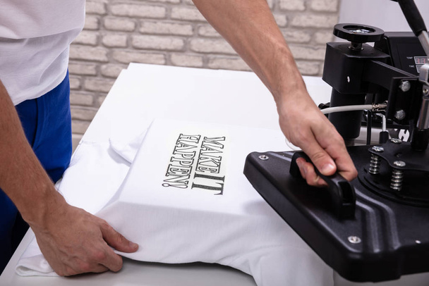 Man printing on t shirt in workshop - Zdjęcie, obraz