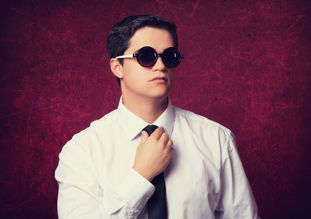 Elegan man in sunglasses at red background. - Foto, Imagen