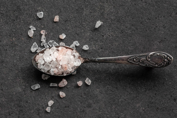 Spoon with Himalayan salt on a black table - Fotó, kép